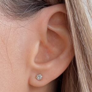 Close-up of a left earlobe with a small round diamond stud earring.