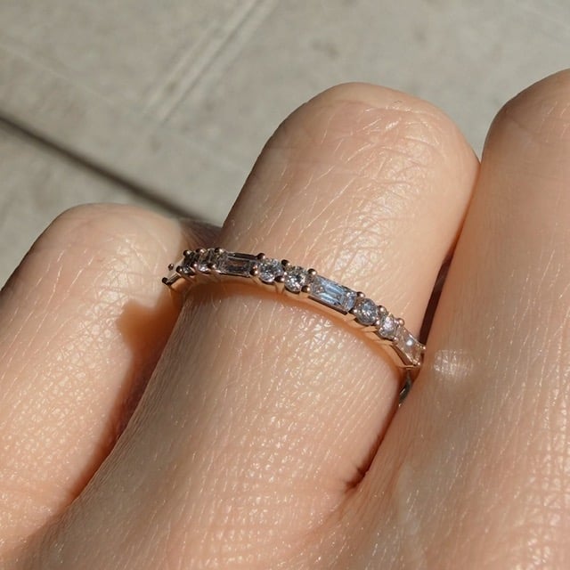 Gold ring with a row of small diamonds on the finger, close-up view in sunlight.