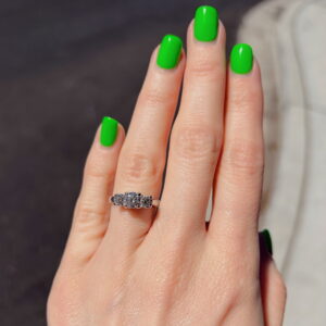 Close-up of a hand with bright green nail polish and a silver ring with clear stones on the ring finger.