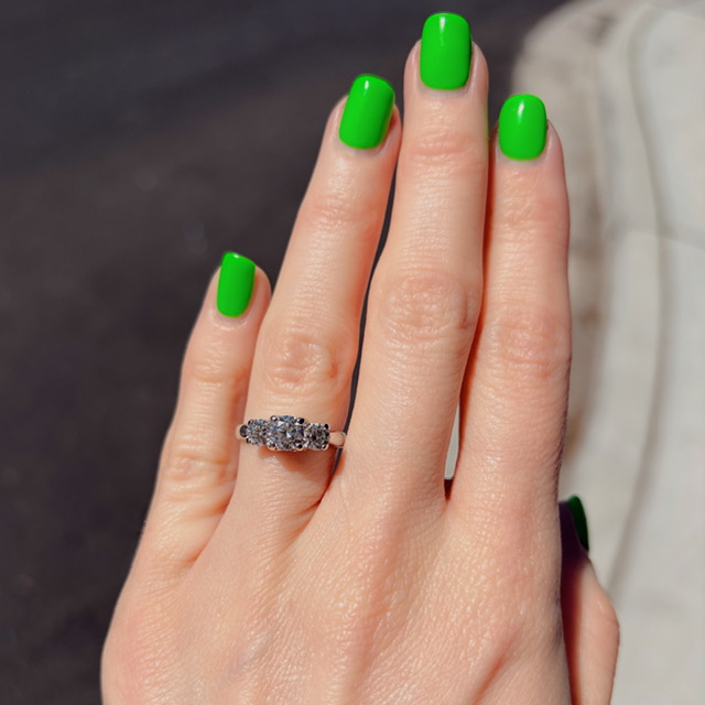 Close-up of a hand with bright green nail polish and a silver ring with clear stones on the ring finger.