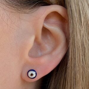 Close-up of a pierced earlobe wearing a round blue-and-white circular stud earring.