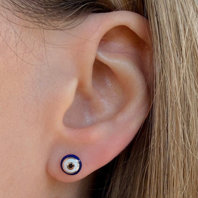Close-up of a pierced earlobe wearing a round blue-and-white circular stud earring.