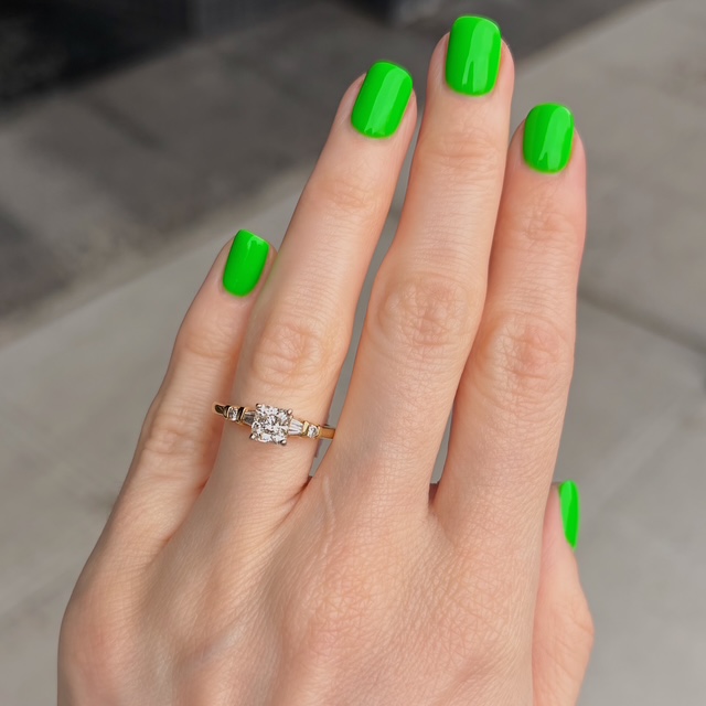 Close-up of a hand with neon green nail polish, showing a gold ring with a diamond on the ring finger