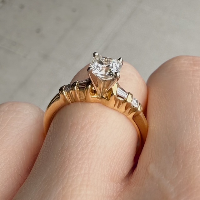 Gold ring with a large diamond solitaire held by six prongs on a finger?