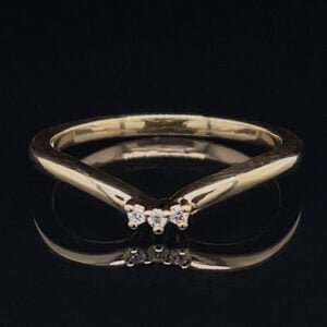 Gold ring with a three-diamond cluster at the top, shown on a black reflective surface.