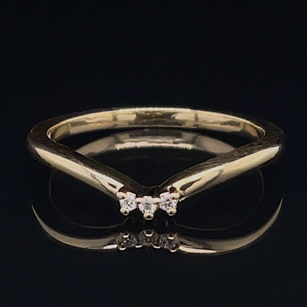 Gold ring with a three-diamond cluster at the top, shown on a black reflective surface.