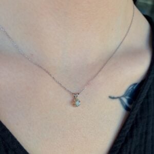 Delicate silver chain necklace with a small round diamond pendant resting on the neck surface