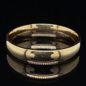 Close-up of a polished gold ring with an interlocking pattern around the band, set against a black background.