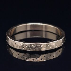 Silver wedding band with a brushed finish and scattered small raised dots on the surface.