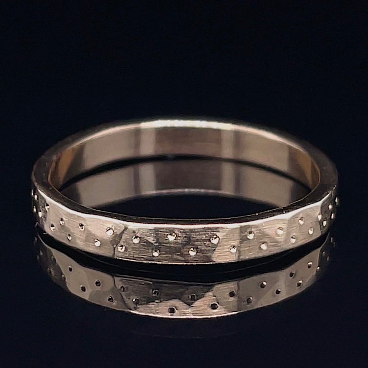 Silver wedding band with a brushed finish and scattered small raised dots on the surface.