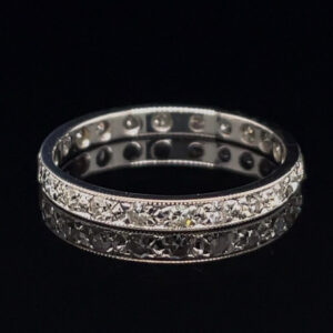 Double-row diamond eternity ring in silver metal on a black background, shimmering stones around the band.