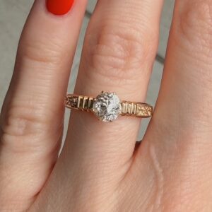 Rose gold engagement ring with a large round diamond on a finger, close-up.