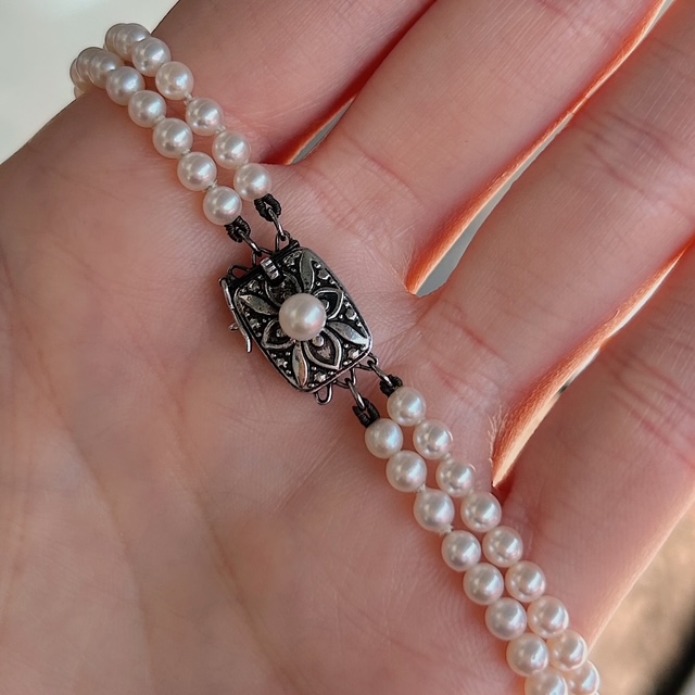 Triple-strand pearl bracelet with an ornate antique-style clasp featuring a central pearl centerpiece.