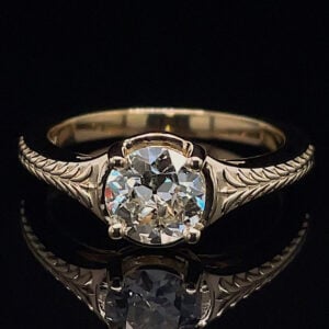 Engagement ring with a large round diamond and a twisted, engraved band on a dark background.