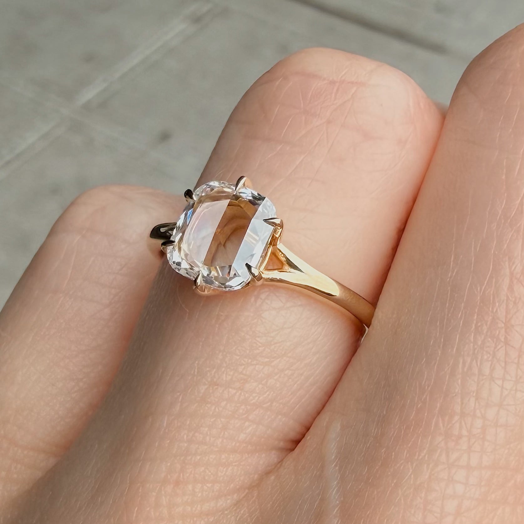 Close-up of a gold engagement ring with a large oval-cut diamond on a finger.