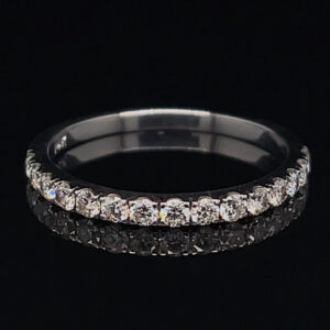 Diamond eternity ring with a row of sparkling stones set around a silver band on a black background, viewed from the side/angled.