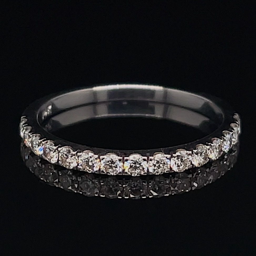 Diamond eternity ring with a row of sparkling stones set around a silver band on a black background, viewed from the side/angled.