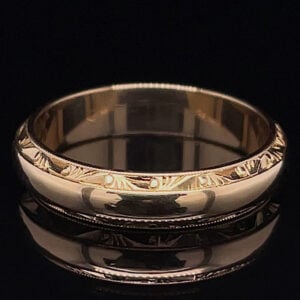 Shiny silver ring with a leaf-like engraved pattern on a black background, close-up