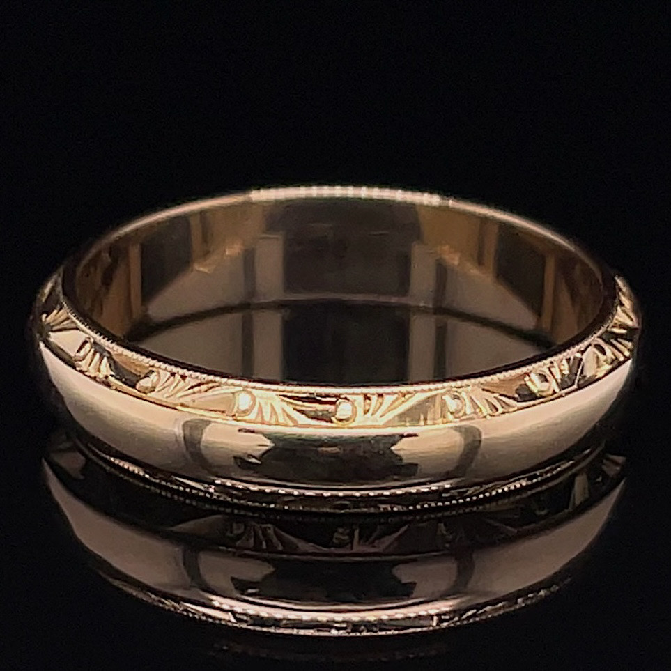 Shiny silver ring with a leaf-like engraved pattern on a black background, close-up