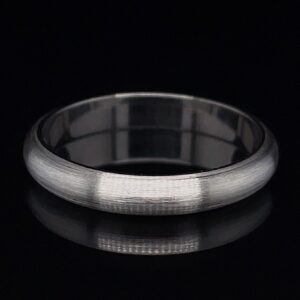Brushed silver wedding band resting on a black background.