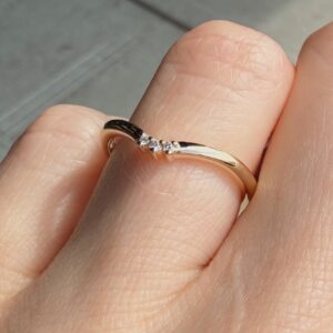 Close-up of a gold ring with a row of small diamonds on the finger.