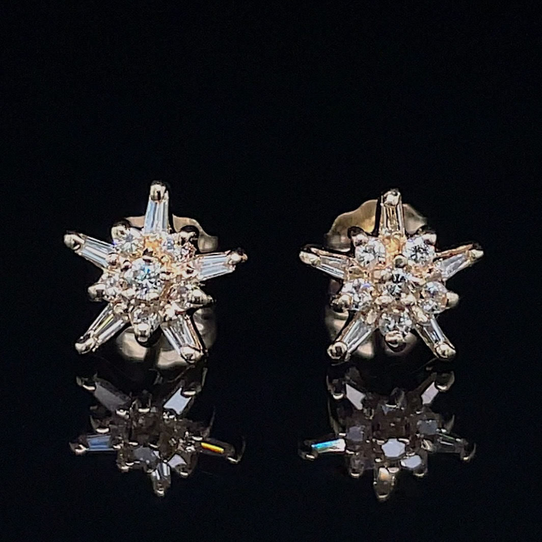 Starburst diamond stud earrings with a central circle of small diamonds and baguette-cut spikes on a black background, reflecting below.