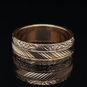 Close-up of a multi-band silver ring with intricate floral engravings and diagonal stripe patterns on a black background.