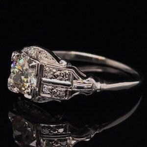 Vintage-style diamond engagement ring with a large central diamond and intricate filigree metalwork on a silver band