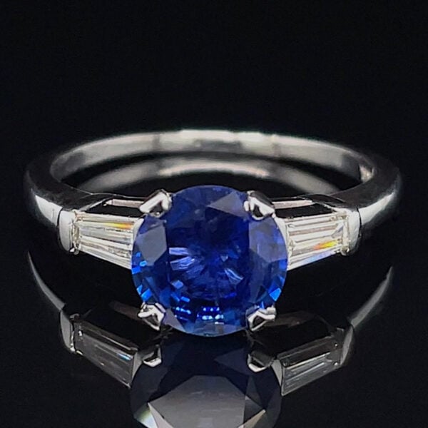 Engagement ring with a large round blue sapphire centerpiece and baguette diamond side stones on a silver band