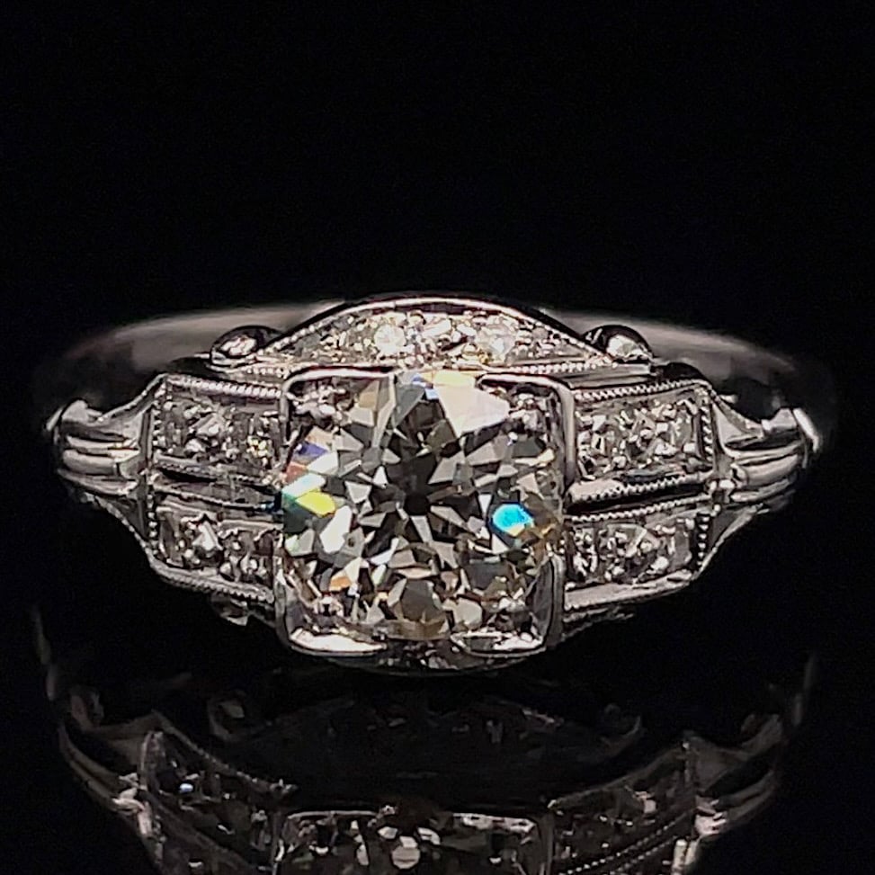 Engagement ring with a large cushion-cut center diamond and pavé side stones in a vintage milgrain platinum setting