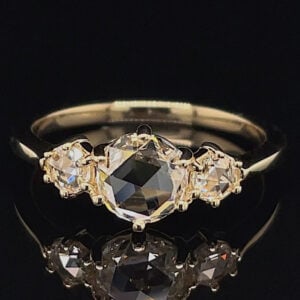 Three-stone ring with a large central dark gemstone and two clear side stones on a gold band.