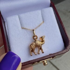 Gold elephant pendant necklace in an open jewelry box with white cushioned lining.