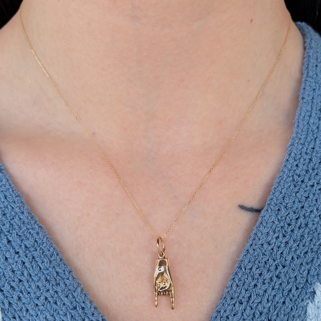 Delicate gold chain necklace with a small pendant hanging down, shaped like an abstract animal figure.