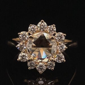 A gold ring with a large central diamond surrounded by a halo of smaller diamonds in a flower-like arrangement.