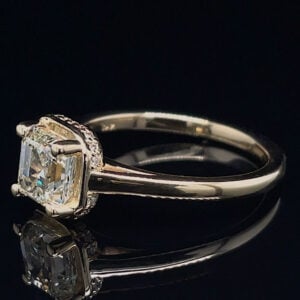 Diamond engagement ring with a cushion-cut center stone and halo of smaller diamonds on a dark reflective surface, close-up view.