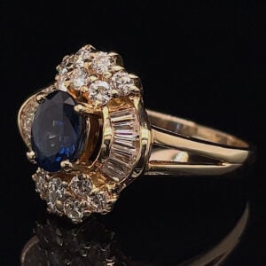 Gold ring featuring a large oval deep-blue sapphire encircled by a halo of round diamonds on a yellow-gold setting.