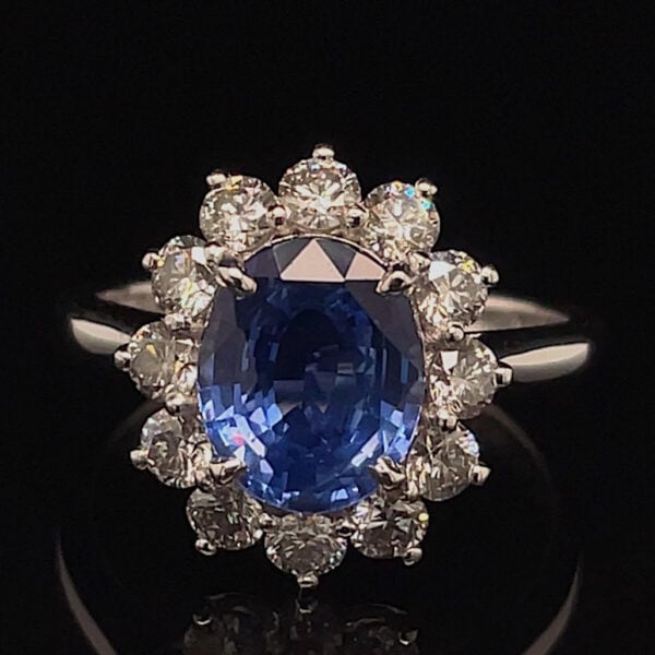 Oval blue sapphire halo ring with a circle of diamonds on a silver band edge-to-edge.