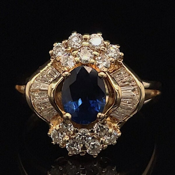 Gold ring with an oval blue sapphire center surrounded by a halo of diamonds on a dark background.