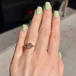 Hand with mint green manicured nails wearing a gold ring with a square-cut diamond on the ring finger.