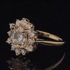 Gold engagement ring with an oval central diamond and a halo of small diamonds on a dark background.