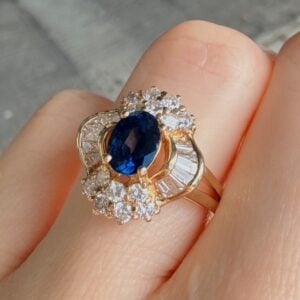 Gold ring featuring a deep blue oval sapphire center surrounded by a halo of diamonds on a gold band.