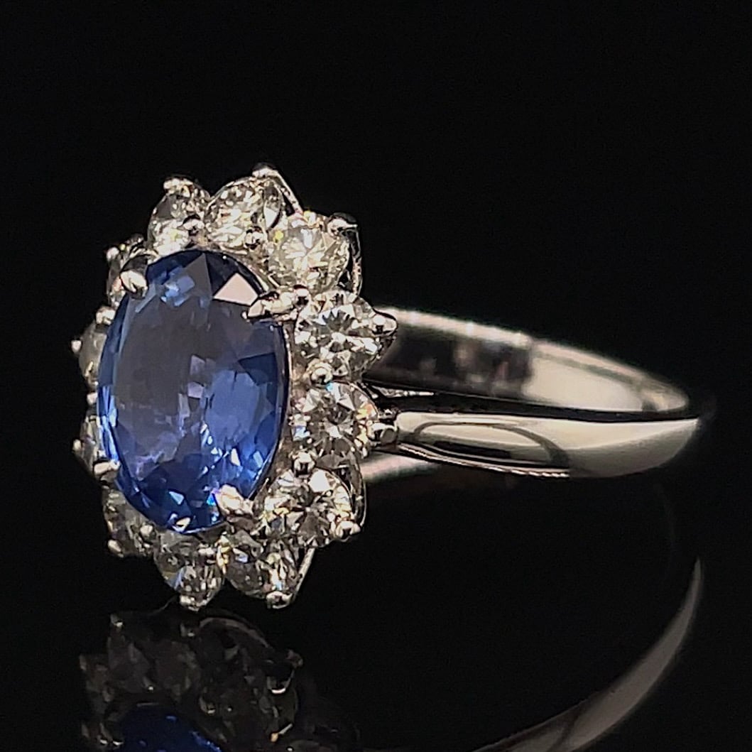 Oval blue sapphire ring surrounded by a diamond halo on a silver band.