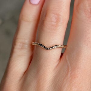 Close-up of a delicate twisted gold ring on a finger.