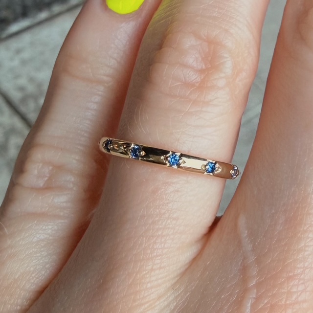 Gold ring with blue stones worn on a finger (close-up).?