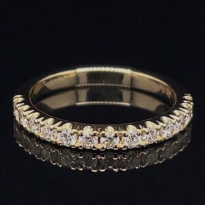 Gold band encrusted with small diamonds, photographed on a black reflective surface (diamond eternity-style ring).