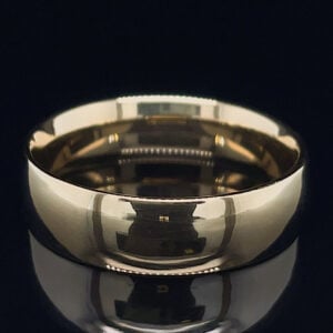 Polished metal wedding band with a highly reflective surface on a dark background.