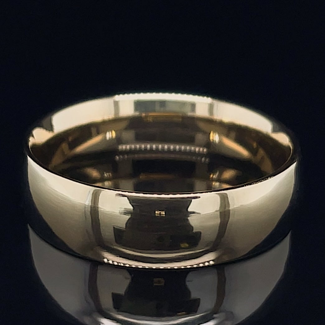 Polished metal wedding band with a highly reflective surface on a dark background.