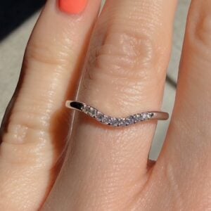 Rose-gold ring with a curved row of tiny diamonds worn on a finger