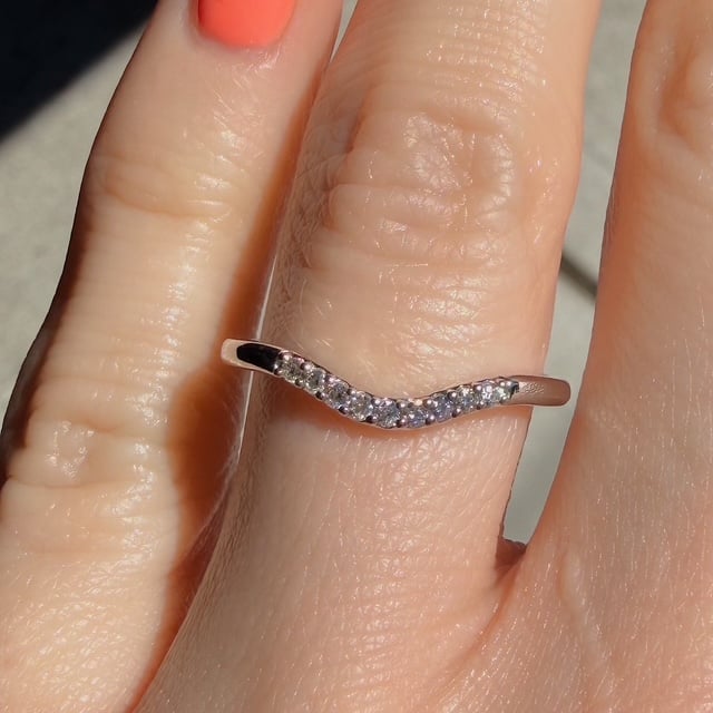 Rose-gold ring with a curved row of tiny diamonds worn on a finger