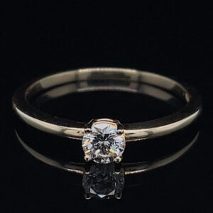 Diamond solitaire ring on a silver band, displayed on a black reflective surface.